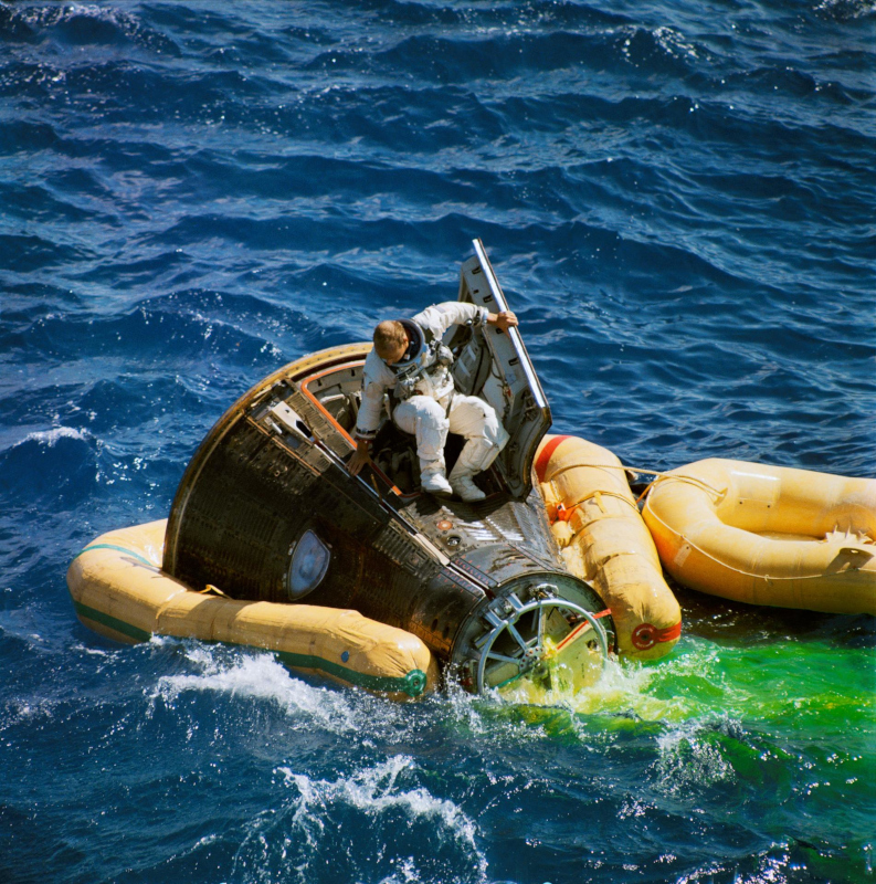 With his Gemini 11 capsule stabilise with yellow floatation devices, Conrad climbs out of the spacecraft ready to jump into a waiting dinghy following splashdown