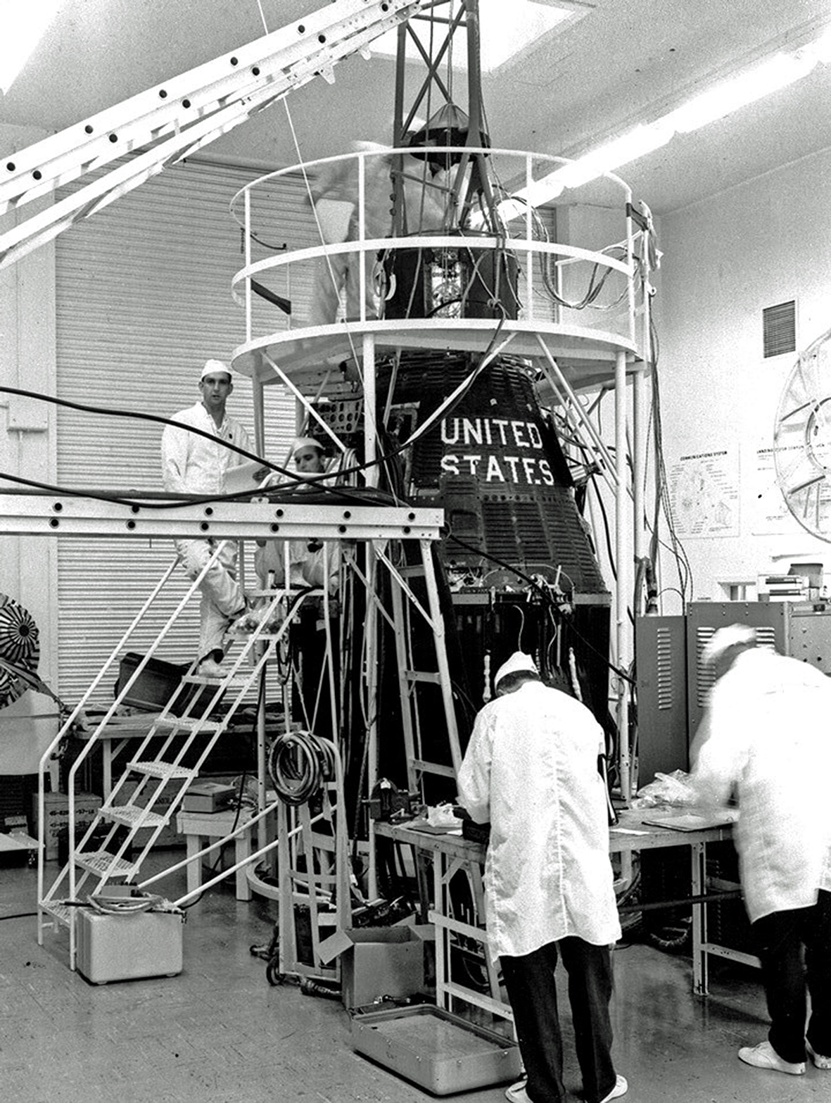 Technicians work on the Aurora 7 capsule during testing in the White Room