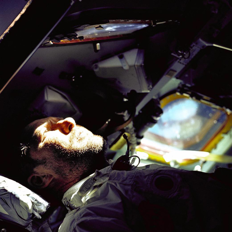 lying on his back, mission commander Schirra looks out of the rendezvous window during the Apollo 7 mission