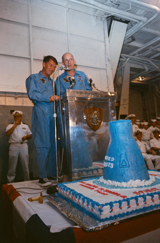 gemini 6 astronauts Schirra and Stafford stand at a lectern to address the crew aboard the recovery ship at the end of their mission